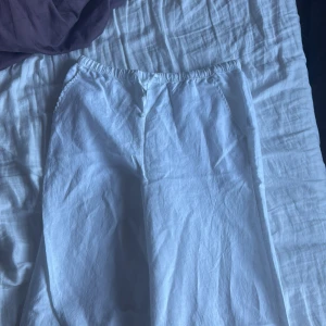 Vita linnebyxor från Kappahl - Säljer ett par vita linnebyxor från Kappahl med avslappnad passform och resår i midjan. Perfekta för sommaren och lätta att matcha med olika toppar. Materialet är luftigt linne som ger en skön känsla hela dagen.