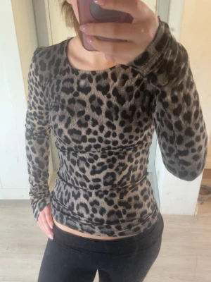 Leopardmönstrad topp från Gina Tricot - Snygg långärmad topp från Gina Tricot med leopardmönster i beige och svart. Toppen har en tight passform och rund halsringning💕Kolla in min profil för fler fina och trendiga plagg!
