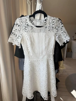 Vit spetsklänning med blommönster - Superfin vit kortklänning i spets med blommigt mönster och korta ärmar. Klänningen har rund halsringning och dragkedja i ryggen. Perfekt för student och sommarens alla tillfällen och ger en romantisk vibe från bubbleroom. Väldigt fint skick och endast använd en gång. Storlek 32.