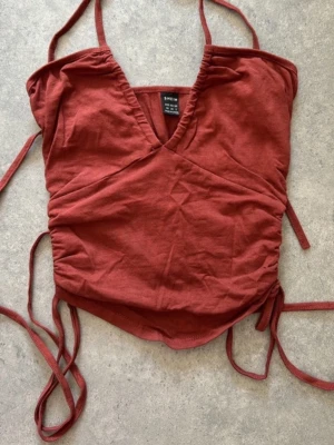 Rostbrun omlottopp från SHEIN - Trendig rostbrun omlottopp från SHEIN med smala axelband och knyt i sidorna. Toppen har v-ringning och är ärmlös, perfekt för en snygg och avslappnad stil. Tillverkad i mjuk bomullsmix för skön känsla.