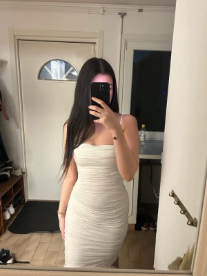 Vit tight klänning med smala axelband - En super fin klänning som är alldeles för liten för mig, endast använd 1 gång, har inga defekter🤗  Vit/krämfärgad  Dubbeltyg så den är inte genomskinlig  XXS Slutar efter knäna (jag är 163 cm)