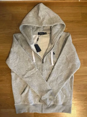 Grå hoodie från Polo Ralph Lauren - Snygg grå hoodie från Polo Ralph Lauren med dragkedja framtill. Den är äkta. hör av er vid snabb affär. 