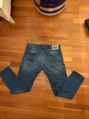 Blå jeans Replay - Säljer ett par blå jeans från Replay med klassisk femficksdesign och snygga detaljer på bakfickorna. Jeansen har en slim fit och är i storlek 34/32. Dem är i mycket bra skick.