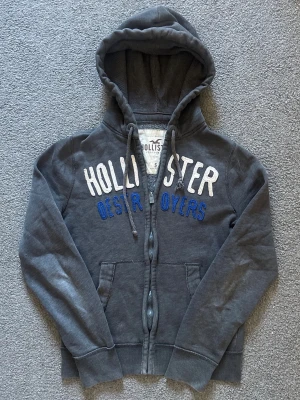 Vintage Hollister Zip-Hoodie - Säljer denna riktigt feta hollister koftan | Storlek S | mycket bra skick förutom litet hål vid vänster armhåla (se sista bild) syns knappast | Modell 175cm, 69kg | Längd≈61cm, bredd armhåla- armhåla ≈ 51cm