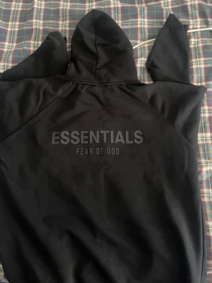 Essentialis - fear of god hoddie  - En svart skön essentials hoddie som sitter riktigt skönt mellan armar och överkropp den är xl men passar xxl med riktigt bra. Pris kan diskuteras 