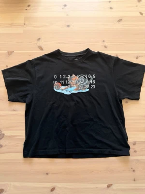 Svart t-shirt med kattmotiv - T shirt från maison margiela i storlek XL.