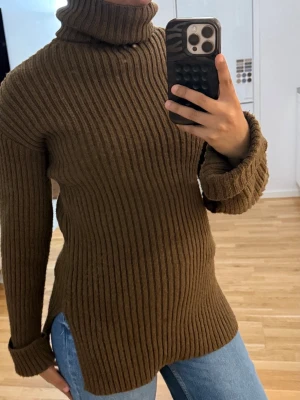 Brun ribbstickad polotröja NAKD  - Säljer en brun ribbstickad polotröja med hög krage och långa ärmar. Tröjan har en relaxed fit och slitsar i sidorna, vilket ger en snygg och avslappnad look. Perfekt att styla med jeans eller kjol. Materialet känns mjukt och värmande. Strl XXS men jag bär s/m och den passar bra. Ord.pris 599