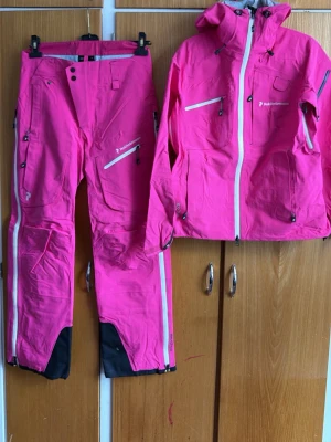 Rosa skaljacka från Peak Performance - Säljer en snygg skaljacka från Peak Performance med vita dragkedjor . Perfekta för skidåkning eller vinteraktiviteter.