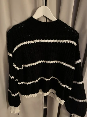 Svart stickad tröja med vita ränder - Säljer en svart stickad tröja med breda vita ränder. Tröjan har ribbstickad hals, muddar och nederkant i vitt. Från SHEIN i storlek M