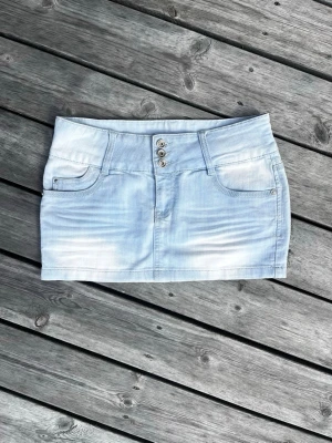 Ljusblå jeanskjol  - Säljer en ljusblå vintage jeanskjol med tre silverfärgade knappar framtill och klassiska fickor både fram och bak. 