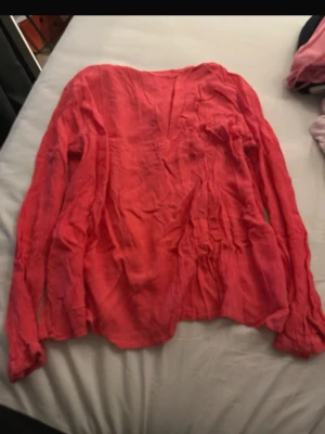 Ljusrosa topp med spets och volang - Supersöt ljusrosa topp från Gina Tricot med långa ärmar, spetsdetaljer längs ringningen och framtill samt en liten rosett. Modellen är croppad med volangkant nedtill och har en feminin, romantisk vibe. Perfekt att styla med jeans eller kjol.