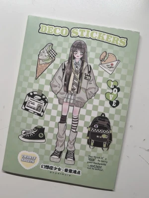 Stickerbok med kawaii anime-inspirerade dekaler - Stickerbok med 10 sidor fyllda med anime-inspirerade dekaler. Motiven inkluderar tecknade tjejer, accessoarer, mat, hjärtan och textbubblor. Omslaget är grönt med rutmönster och insidan har rosa bakgrund. Perfekt för att dekorera anteckningsböcker, mobilskal eller brev.
