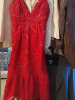 Röd spetsklänning med volang - Snygg röd kortklänning med spetsdetaljer och volang nedtill. Klänningen har v-ringad urringning och tunna axelband. Perfekt för dig som vill sticka ut med ett elegant och trendigt plagg.