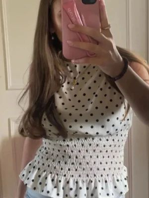 Vit prickig topp - Så fin vit topp med svarta prickar och smockad midja! Väldigt populär och helt nytt skick🩷🩷