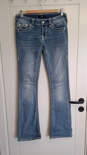 Ljusblå bootcut jeans från true religion  - Snygga ljusblå bootcut jeans från true religion med markerade kontrastsömmar. Klassisk femficksmodell och låg midja. Jeansen har en tvättad look och är tillverkade i denim med stretch för extra komfort.
