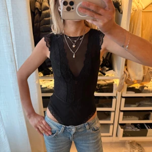 Svart spetsbody med meshdetaljer HM body - Snygg svart body med spetsdetaljer och mesh upptill från HM. Djup v-ringning med spetskant och breda axelband. Kroppsnära passform och genomskinliga partier ger en trendig look. Perfekt att styla med jeans eller kjol för en cool outfit. HM body, body från HM. Passar mig med S. Passar nog Xs också