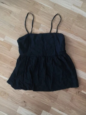 Svart linnetopp med tunna axelband - Sart peplum top med tunna axelband.