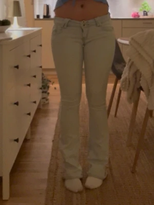 Ljusblå bootcut jeans - Säljer ett par ljusblå bootcut jeans med klassisk femficksdesign och normal midja. Jeansen har en snygg, lätt utsvängd passform nedtill och stängs med dragkedja och knapp. Perfekta för dig som gillar en retroinspirerad look.