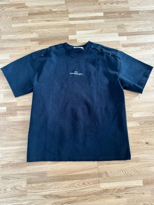 Svart t-shirt från MM6 Maison Margiela - Cool svart t-shirt från MM6 Maison Margiela med vit text på bröstet. Klassisk rund halsringning och raka, korta ärmar. T-shirten har en minimalistisk design och är tillverkad i mjuk bomull och sitter oversized 