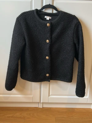 Svart bouclékofta med guldknappar - Stilren svart kofta i bouclématerial med rund halsringning från Gina Tricot 💫💫 Lite större i storlek, passar dig som är xs/s