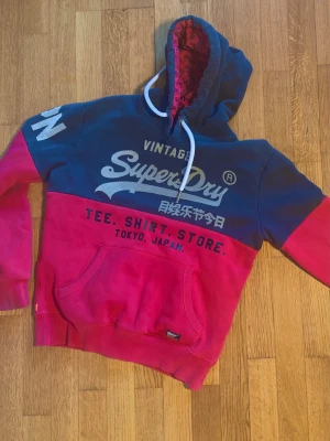 Sällsynt Superdry Vintage Hoodie - En supersnygg Superdry hoodie i stil inspirerad från japansk vintage. Mycket populär typ av tröja just nu, och dessutom i en riktigt snygg modell och färg🤩Etiketten visar stl S och den passar även därefter. Tröjan sitter supersnyggt och är helt utan fläckar med tyg i superfint skick👌vi luvöppningen finns en ytterst liten defekt som inte är märkvärdig vid användning. Det som hänt är att en tråd gått av just där👈Syns på bild 3 och 4👍 Tröjan passar superbra på personer mellan 170-176 cm.