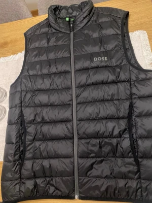 BOSS väst herr  - Säljer en fin väst i storlek XXL, liten i storleken! Den är använd en säsong så den är som ny i skicket.  Nypris är 2400kr! Perfekt nu till våren!