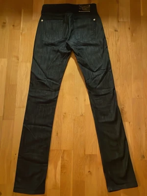 Svarta låg midjade Jeans  - Svarta lågmidjade jeans från Faith i storlek 25! Dom har en urtvättad look och har fina vingar som detalj på en av fickorna. Jeansen är i mycket bra skick! Midjemått: 31cm  Längd: 106cm. Innerbenslängd: 85cm! Pris kan diskuteras🥰