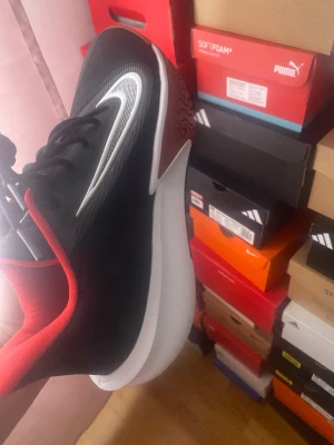 Svarta Nike sneakers med röd detalj - Snygga svarta Nike sneakers med vit swoosh och röda detaljer på insidan och sulan. Skon har en modern design med tjock vit mellansula och svart ovandel i syntetmaterial. Perfekt för dig som gillar sportig och stilren look.