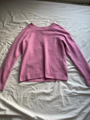Rosa stickad tröja från Vero Moda - Mysig rosa stickad tröja från Vero Moda med rund halsringning och ribbade muddar vid ärmslut och nederkant. Materialet är mjukt och behagligt mot huden.
