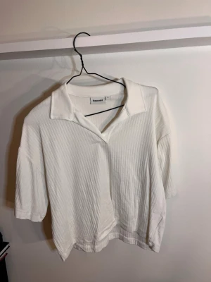 Vit topp S (M) - Vit ribbad topp från Kappahl med krage och v-ringning. Toppen har korta ärmar och en avslappnad passform. det står storlek S men den är som M / L