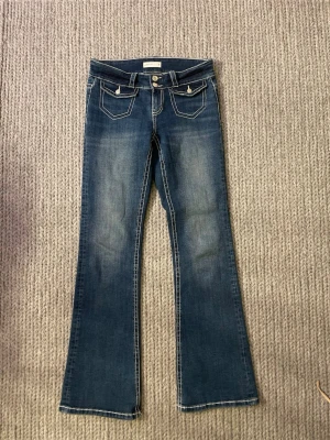 Bootcut jeans med fickdetaljer – Y2K - Jättefina bootcut jeans i mellanblå denim med snygga fickdetaljer fram. De har en riktigt fin passform och lite Y2K känsla. Väldigt lätta att matcha med olika outfits.
