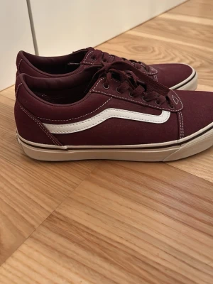 Vinröda Vans Old Skool sneakers - Säljer ett par klassiska Vans Old Skool sneakers i vinrött med vit sidostripes. Skorna har snörning. Perfekta för dig som vill ha en stilren och tidlös look.