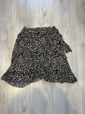 Leopardmönstrad omlottkjol med volang - Jätte fin kort leopardmönstrad omlottkjol med volangkant. Kjolen har en knytning i sidan. På bilderna är kjolen inte struken än, men det gör jag innan köp💞