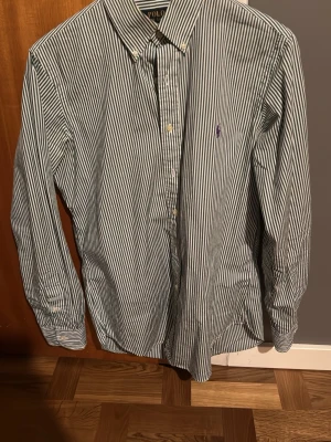 Polo Ralph lauren skjorta - Ralph lauren skjorta med grön/vita ränder. Säljer då den inte riktigt är min stil samt att jag knappt använde den. Hör av dig om du har fler frågor