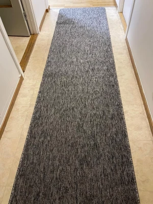 Grå lång matta PORTO 80x320 cm - Säljer en lång och stilren grå matta från PORTO, perfekt för hallen eller korridoren. Mattan är tillverkad i 100% polypropen och har en diskret melerad design som passar in i de flesta hem. Enkel att hålla ren och har OEKO-TEX certifiering. Nästan helt nytt skick!
