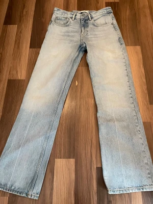 Ljusblå raka jeans från Zara - Säljer ett par ljusblå jeans från Zara med rak passform och klassisk femficksdesign. Jeansen är tillverkade i denim och har en snygg, lite tvättad look. Perfekta för dig som gillar en avslappnad och trendig stil.38