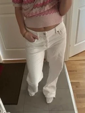 Vita raka jeans från Zara med låg midja - Säljer ett par vita jeans med rak passform och låg midja. Jeansen har klassisk femficksdesign och bälteshällor. Perfekta att styla med en crop top eller hoodie för en clean look.