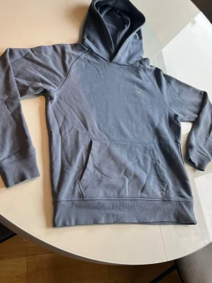 Gant hoodie - Snygg blå hoodie. Tillverkad i mjukt bomullsmaterial. Minimalistisk design med liten diskret logga på bröstet. Perfekt för en avslappnad och stilren look.