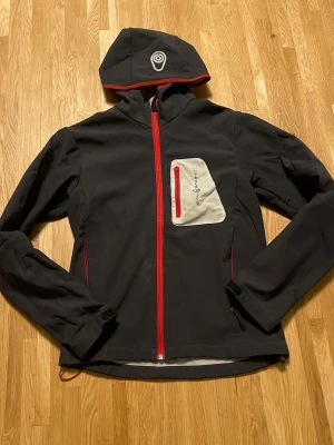 Sail racing jacka  - Bra skick lite smuts som går bort, ena spännaren är trasig men går säkert att fixa men behövs oftast inte spänna jackan nere, finns en till spännaren på andra sidan, 