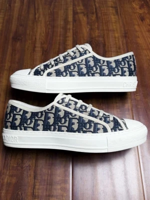 Dior Oblique låga sneakers - Snygga låga sneakers från Dior med klassiskt blått och vitt Oblique-mönster. Skorna har vita snören, vit sula och detaljer med 'CHRISTIAN DIOR' på sidan och hälen. Ovandelen är i textil och sulan i gummi. Perfekta för en trendig och exklusiv look.