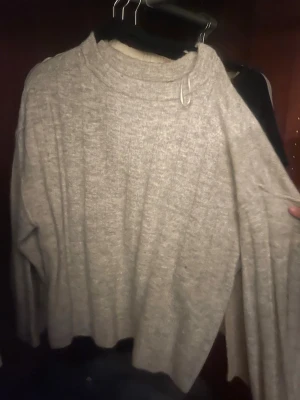 Grå oversized stickad tröja - Mysig grå stickad tröja med oversized passform och rund hals. Tröjan har långa ärmar och ribbade muddar vid halsen. Perfekt för lager på lager och enkel att matcha med olika outfits.