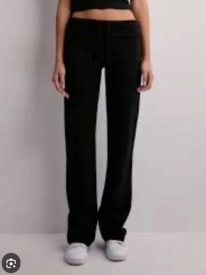 Svarta mjukisbyxor med dragsko - Säljer ett par svarta mjukisbyxor med raka ben och dragsko i midjan. Byxorna har en avslappnad passform och är tillverkade i ett mjukt och stretchigt material som känns skönt mot huden. Perfekta för chill dagar eller när du vill vara bekväm. Ifrån Nelly 