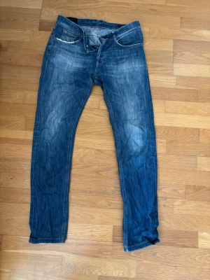 Blå jeans från dondup med raka ben - Snygga blå jeans från domdup med klassisk femficksmodell och raka ben. Jeansen har slitningar och ljusare partier framtill och baktill för en trendig, använd look. Tillverkade i denim med kontrastsömmar och normal midja.