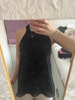 Svart ärmlös topp från Zara Basic - Säljer en svart, stilren ärmlös topp från Zara Basic Collection. Toppen har hög hals och rak passform, perfekt att matcha med både jeans och kjol. Materialet känns lätt och svalt, vilket gör den skön att bära under varma dagar.