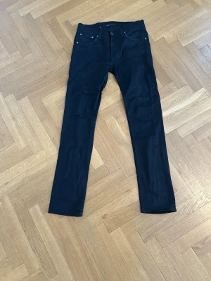 Svarta slim jeans från Nudie Jeans - Säljer ett par svarta slim fit jeans från Nudie. Jeansen är tillverkade i ett stretchigt bomullsmaterial som ger en skön passform. Byxorna är riktigt feta och dom är använda ett fåtal gånger men du som köpare kommer förändra byxorna. Då byxorna ändras efter ett tag som gör alla nudie jeans unika. Ett par svarta slim fit jeans sitter aldrig fel. Hör av dig vid frågor och funderingar. 