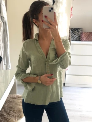 Linneskjorta från Zara - Snygg ljusgrön skjorta i linne med v-ringning och knappar framtill. Skjortan har lång ärm som kan vikas upp och en bröstficka. 