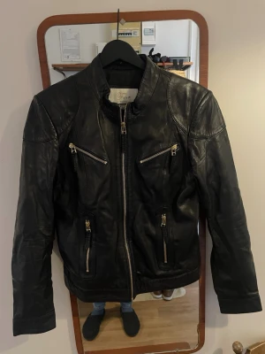 Furst Denmark Skinnjacka - Snygg svart skinnjacka från Furst Denmark  med fyra dragkedjefickor framtill och coola detaljer på axlar och ärmar. Jackan har en rak passform och hög krage med tryckknapp. Perfekt för dig som vill ha en klassisk bikerstil.