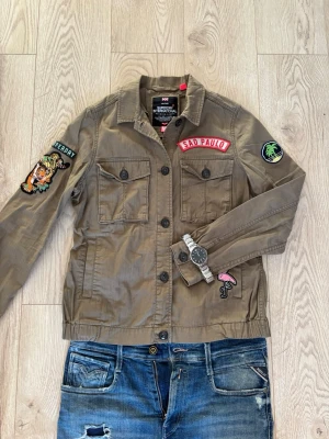 Overshirt från Superdry - Ruskigt snygg overshirt från Superdyr men snygga patches. Perfekt nu när våren börjar närma sig. Storleken är M men den sitter som en S. Tveka inte på att höra av dig om du har frågor!
