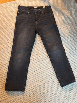 Mörkblå raka jeans - Säljer ett par mörkblå jeans med rak passform och klassisk femficksdesign. Jeansen har normal midja och är tillverkade i denim med lätt tvättad look. Byxorna är uppsydda vid benen så jag skulle nog säga att storleken är 33/30 eller 29 istället för 33/32