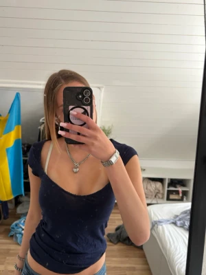 Mörkblå croppad v-ringad topp från Nelly - Trendig mörkblå topp med v-ringning och croppad passform. Kortärmad modell i mjukt material, perfekt för en avslappnad och snygg stil. Enkel att matcha med jeans eller kjol.